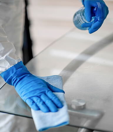 Gloved hand wiping a glass table